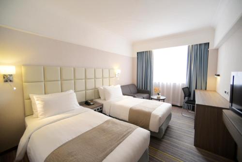 ein Hotelzimmer mit zwei Betten und einem Fernseher in der Unterkunft Panda Hotel in Hongkong