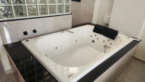 a white tub in a bathroom with a black counter at Vila Caluca Olimpia - Flats & Suites in Olímpia