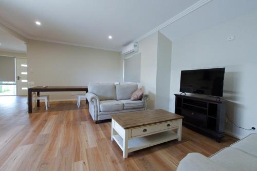 a living room with a tv and a couch and a table at South West Retreat in Bunbury
