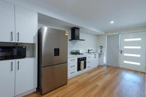 a kitchen with a stainless steel refrigerator and white cabinets at South West Retreat in Bunbury