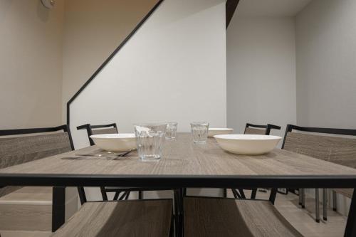 a dining room table with bowls and glasses on it at 匠の家 大阪城近くの高級感あふれる吹き抜けの家 A Luxurious Home with a Grand Atrium Near Osaka Castle in Osaka