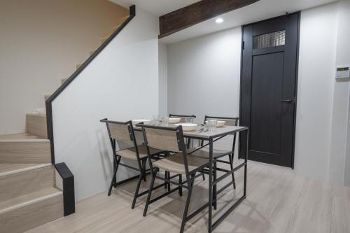 a dining room with a table and chairs and a black door at 匠の家 大阪城近くの高級感あふれる吹き抜けの家 A Luxurious Home with a Grand Atrium Near Osaka Castle in Osaka