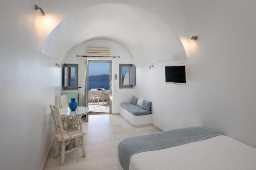 a bedroom with a bed and a table with a view of the ocean at Iliovasilema Suites in Imerovigli