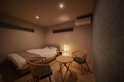 a bedroom with a bed and a table and chairs at 湯宿灯火 in Beppu