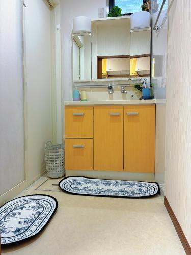 a kitchen with orange cabinets and two rugs on the floor at Koyasui Guesthouse for Groups Easy Access to Yokohama & Shin-Yokohama in Yokohama