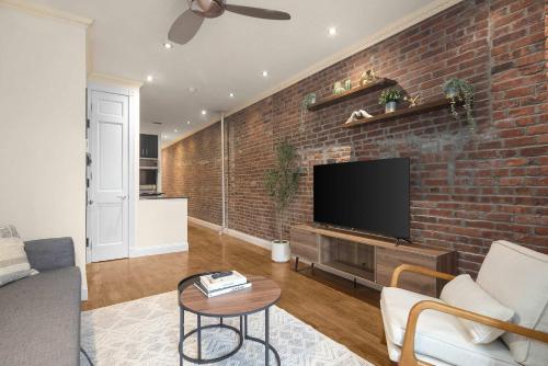 a living room with a brick wall with a flat screen tv at Stylish East Side Escape Steps from Fun in New York
