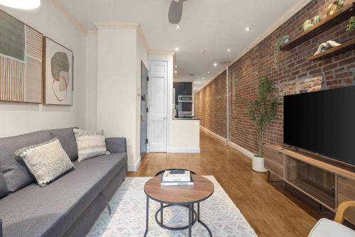 a living room with a gray couch and a brick wall at Stylish East Side Escape Steps from Fun in New York