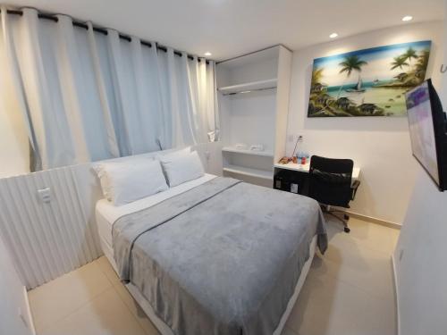 a bedroom with a bed and a desk and a painting at Pousada Dunas Natal in Natal