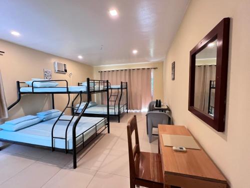 a room with three bunk beds and a table at Boracay Amor Apartment (Garden) in Boracay