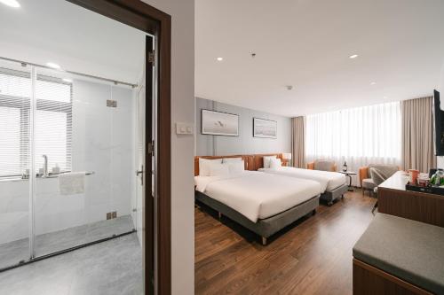 a hotel room with two beds and a bathroom at San Hanoi Hotel & Gaming in Hanoi