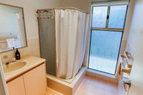a bathroom with a shower and a sink and a window at Ibis Rest Beach House in Geographe