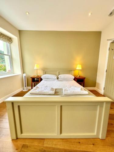 a large white bed in a bedroom with two lamps at RIVERBANC in Llangollen