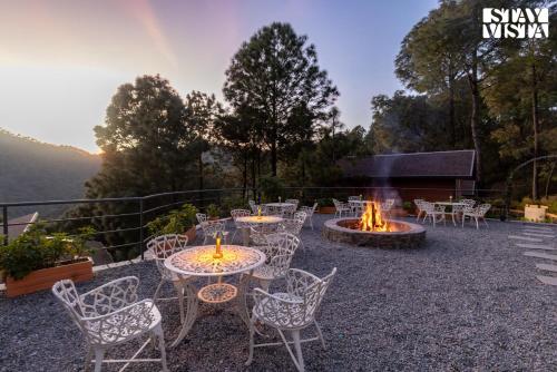 a patio with tables and chairs and a fire pit at Sirmour Baag by Vaana - A part of StayVista in Nahna