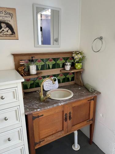 a bathroom with a sink and a mirror at Urunga Fisherman's Cottage - pets ok 15 mins Coffs in Urunga