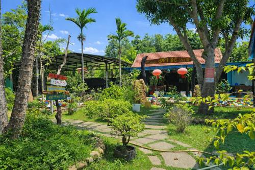 a garden in front of a building with trees at Đồi Dẻ Eco HomeStay in Bố Trạch