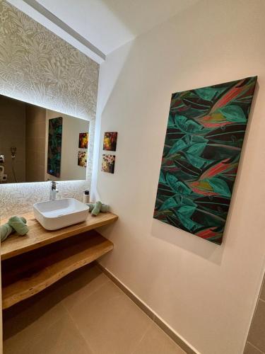 a bathroom with a sink and a painting on the wall at Te mana Dream apartment in Paea
