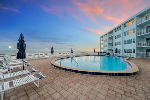 a swimming pool in front of a building and a beach at Paradise Beach Club - Oceanfront Ground Floor Condos with Heated Pool Pets Welcome in Satellite Beach