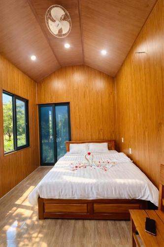 a bedroom with a large bed with wooden walls and windows at Đồi Dẻ Eco HomeStay in Bố Trạch