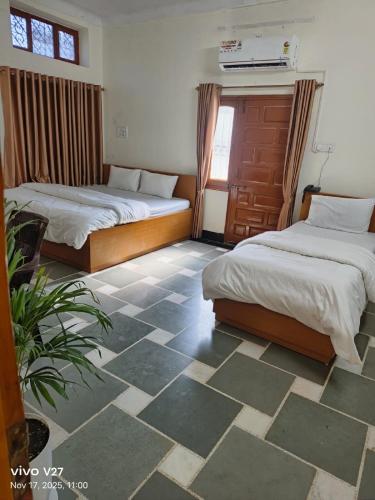 a bedroom with two beds and a tile floor at Riddhi Guest House in Udaipur
