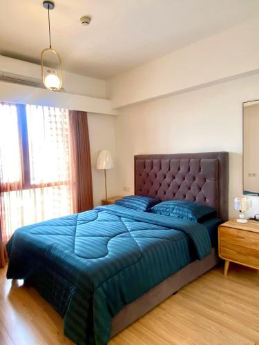 a bedroom with a large bed with a blue comforter at Skyhouse bsd tower duxton 2 in Samporo