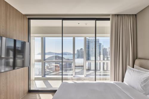 a bedroom with a bed and a large window at Palatium Haeundae by SONO Felice in Busan