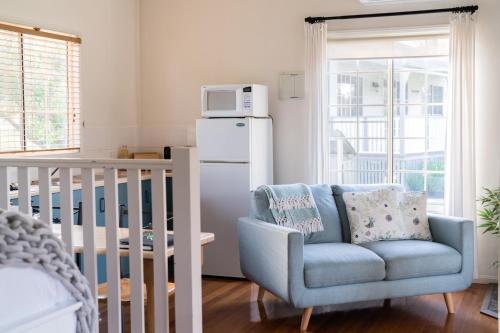 a living room with a blue chair and a white refrigerator at Granite Gardens Cottages & Lake Retreat in Stanthorpe