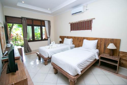 a bedroom with two beds and a television in it at Mina Pelasa Hotel in Legian