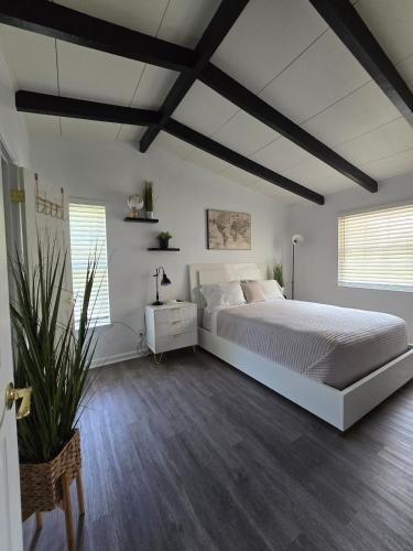 a bedroom with a large white bed and wooden floors at 904 Nomads Nest Mid-Century modern entertainment home with cabin vibes, 2 MEGA gamerooms, pingpong, pooltable, gym, patio in Jacksonville
