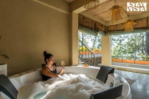 a woman sitting in a bath tub with a glass of wine at Sirmour Baag by Vaana - A part of StayVista in Nahna