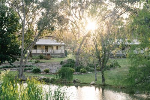 a house in the middle of a lake with trees at Granite Gardens Cottages & Lake Retreat in Stanthorpe