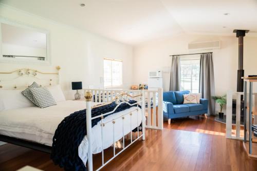 a bedroom with a white bed and a blue chair at Granite Gardens Cottages & Lake Retreat in Stanthorpe