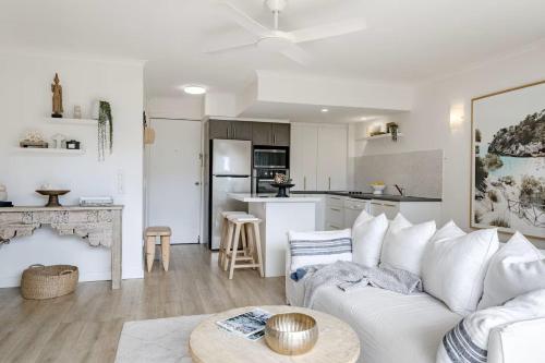 a living room with a white couch and a kitchen at Noosa Parade Holiday Inn in Noosa Heads