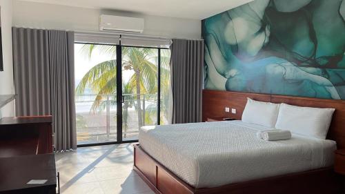 a bedroom with a bed with a painting on the wall at Coco Blue a New Beach Resort in La Libertad