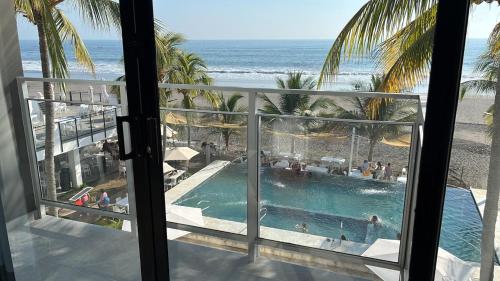 a view of a swimming pool and the beach from a hotel room at Coco Blue a New Beach Resort in La Libertad