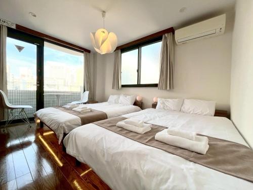 a bedroom with two beds with white sheets and windows at Yokohama Mega Stay in Yokohama