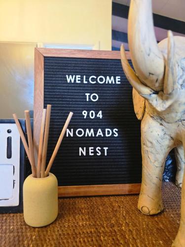 a sign that says welcome to nomads nest next to a statue at 904 Nomads Nest Mid-Century modern entertainment home with cabin vibes, 2 MEGA gamerooms, pingpong, pooltable, gym, patio in Jacksonville