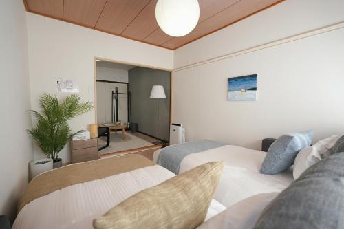 a bedroom with two beds and a living room at INA HOUSE Higashi-Fuchu 101 in Fuchu