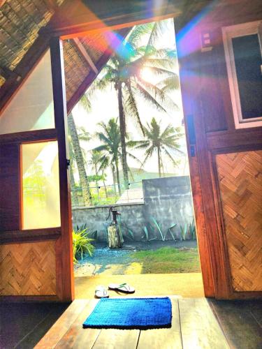 an open door to a room with a palm tree at Duon Baler - Seconds from Sabang beach, your peaceful escape in Baler