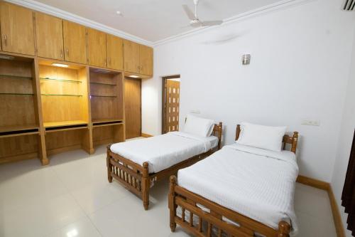 two beds in a room with wooden cabinets at Thaayar Homestay by Highpoint in Tiruchirappalli