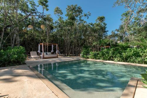 a swimming pool in a backyard with trees at Lumina at LOSANTOS Tulum in Tulum