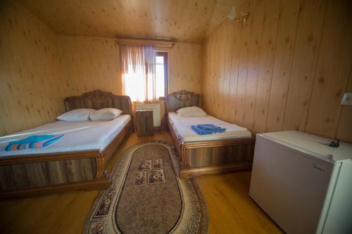 a room with two beds and a refrigerator and a rug at Hotel Nikala in Tskaltubo