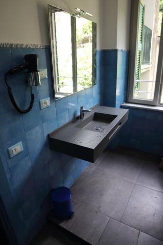 a blue tiled bathroom with a sink and a window at 5 TERRE PELAGOS in Manarola