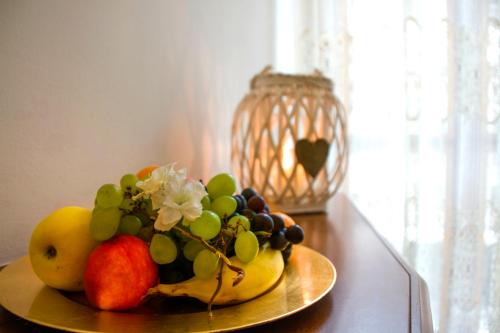 a plate of fruit on a table with a vase at Domus Hotel in Alessandria