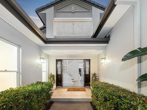 a white house with a door and some plants at Capri Garden Stay in Gold Coast