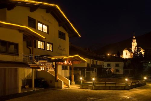 a building at night with a church in the background at Alpenstern rooms & suites in Lermoos