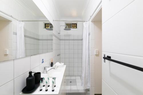 a white bathroom with a sink and a mirror at Nature's Nest - Pool - SPA - Outdoor Kitchen and Dining in Leanyer