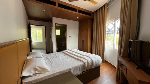 a bedroom with a bed and a flat screen tv at Cloud Nine Hotel in Kottayam