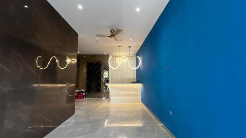 a hallway with a blue wall and chandeliers at Cloud Nine Hotel in Kottayam