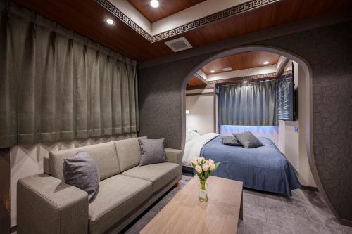 a room with a couch and a bed and a mirror at Hotel FLOW in Misato