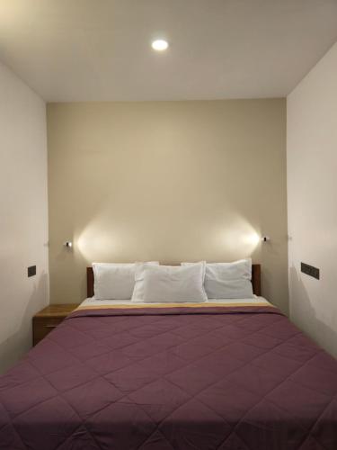 a bedroom with a large bed with a purple blanket at Kubera Heritage Inn , Near Sreepadmanabhaswamy temple in Trivandrum